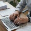 Person working diligently at a desk with paperwork.