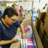 Entrepôt logistique avec chariots élévateurs et employés organisant des colis.